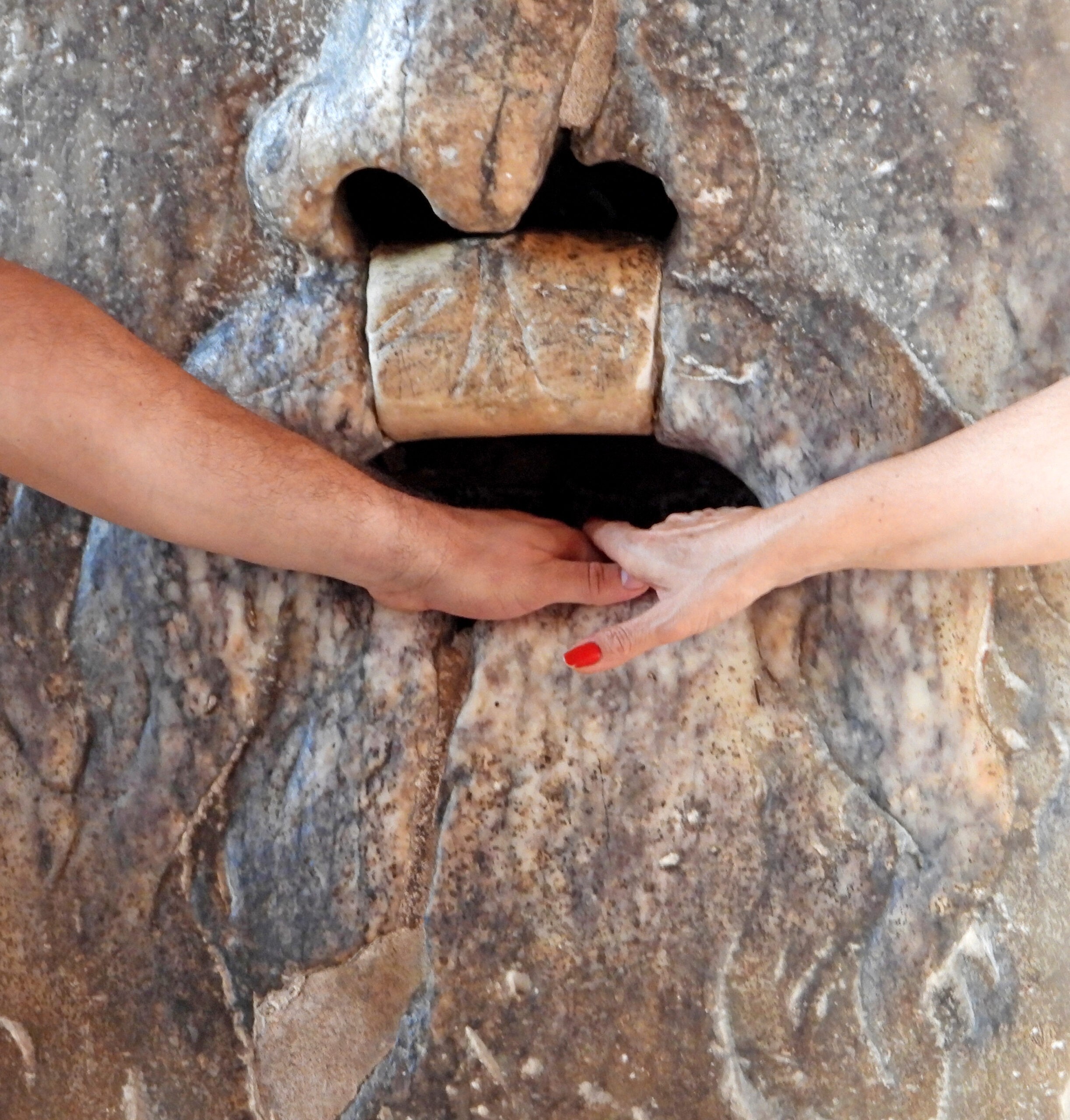 A couple places their fingers in the Mouth of Truth./Getty Images