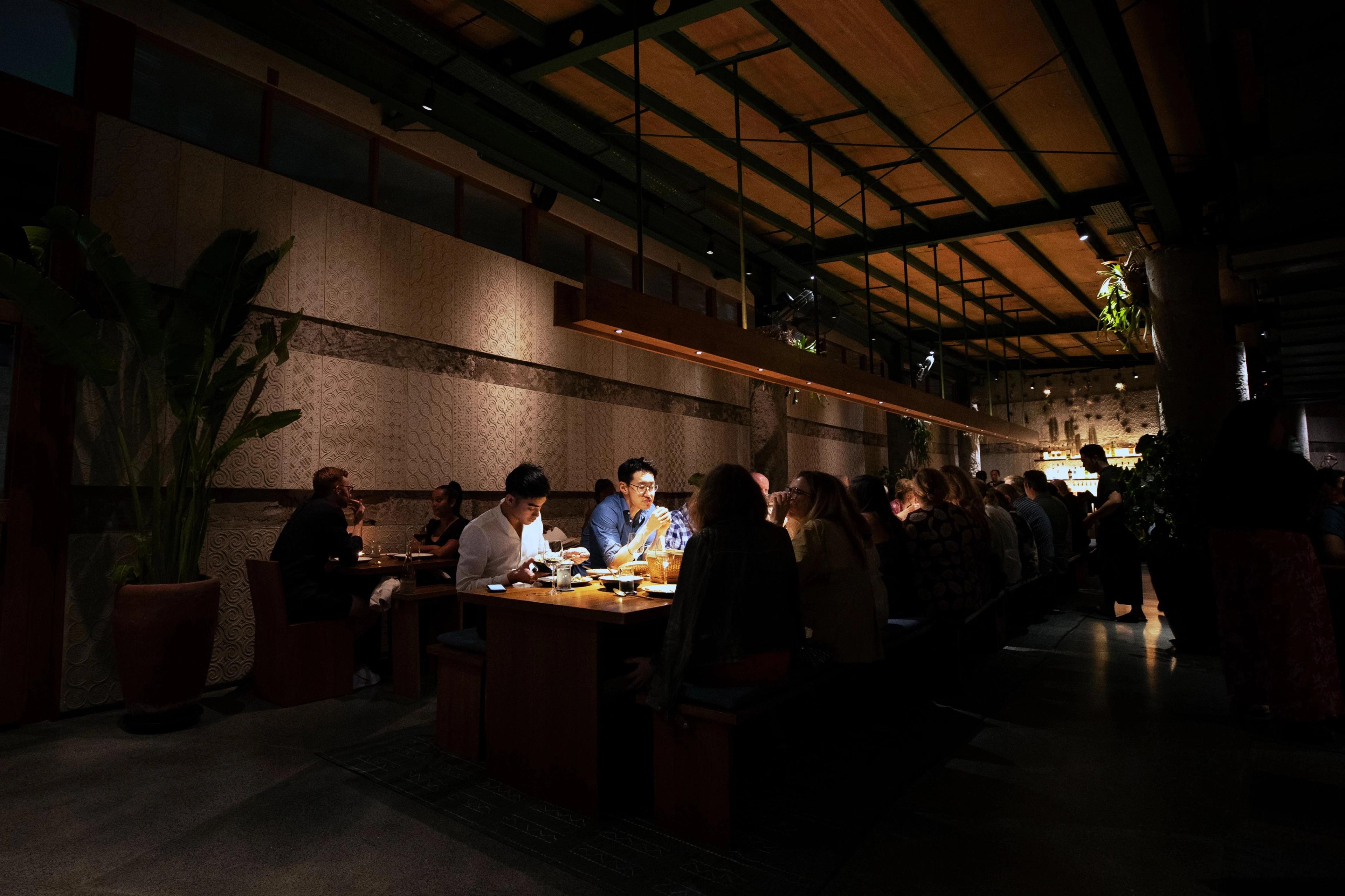 Lively upscale restaurant interior displaying distinct stone textures and multiple guests sharing authentic Balinese cuisine.