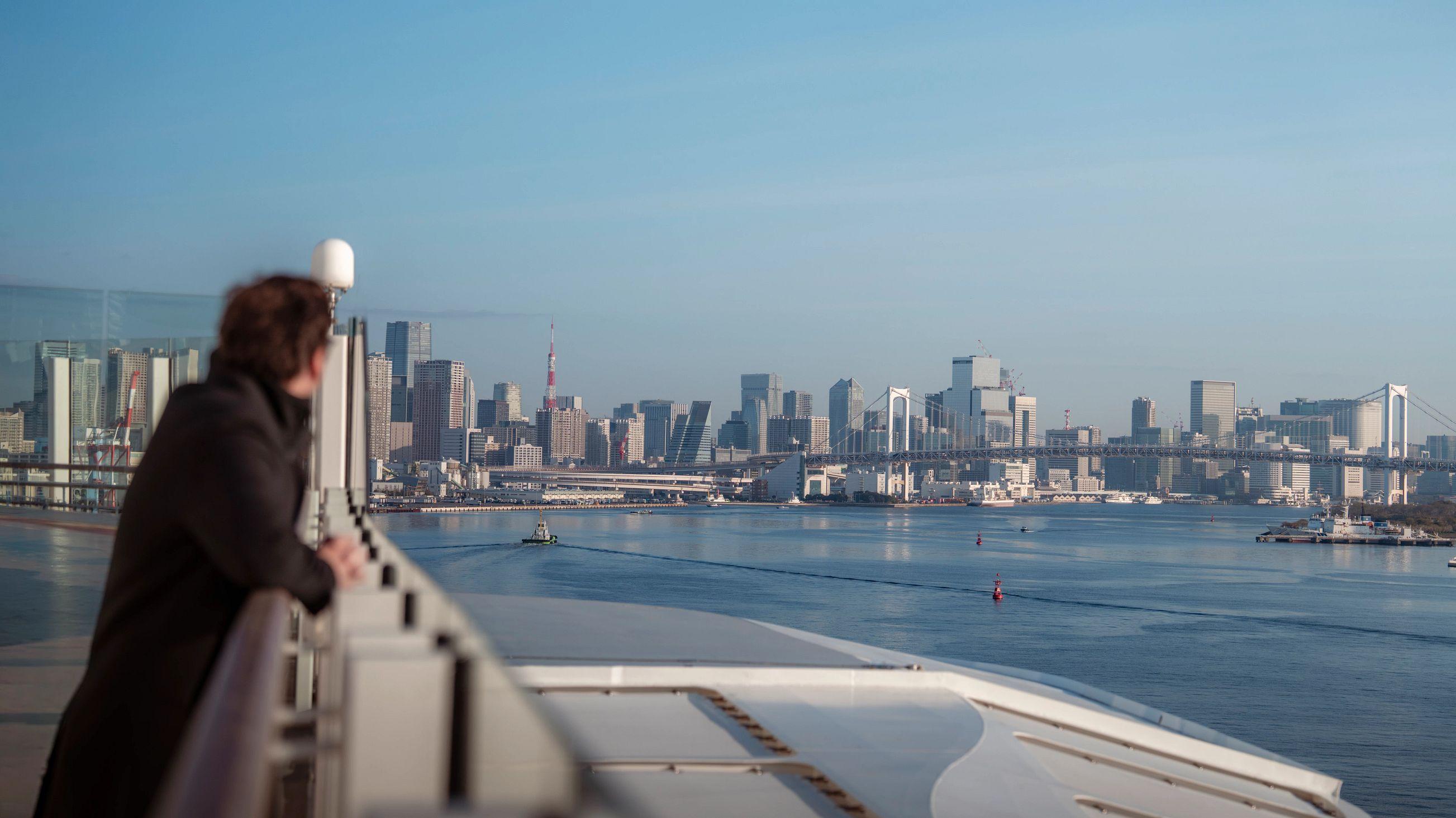 A traveler looks out the horizon of Tokyo Bay, where the big metropolis meets the iconic silhouette of the Rainbow Bridge.