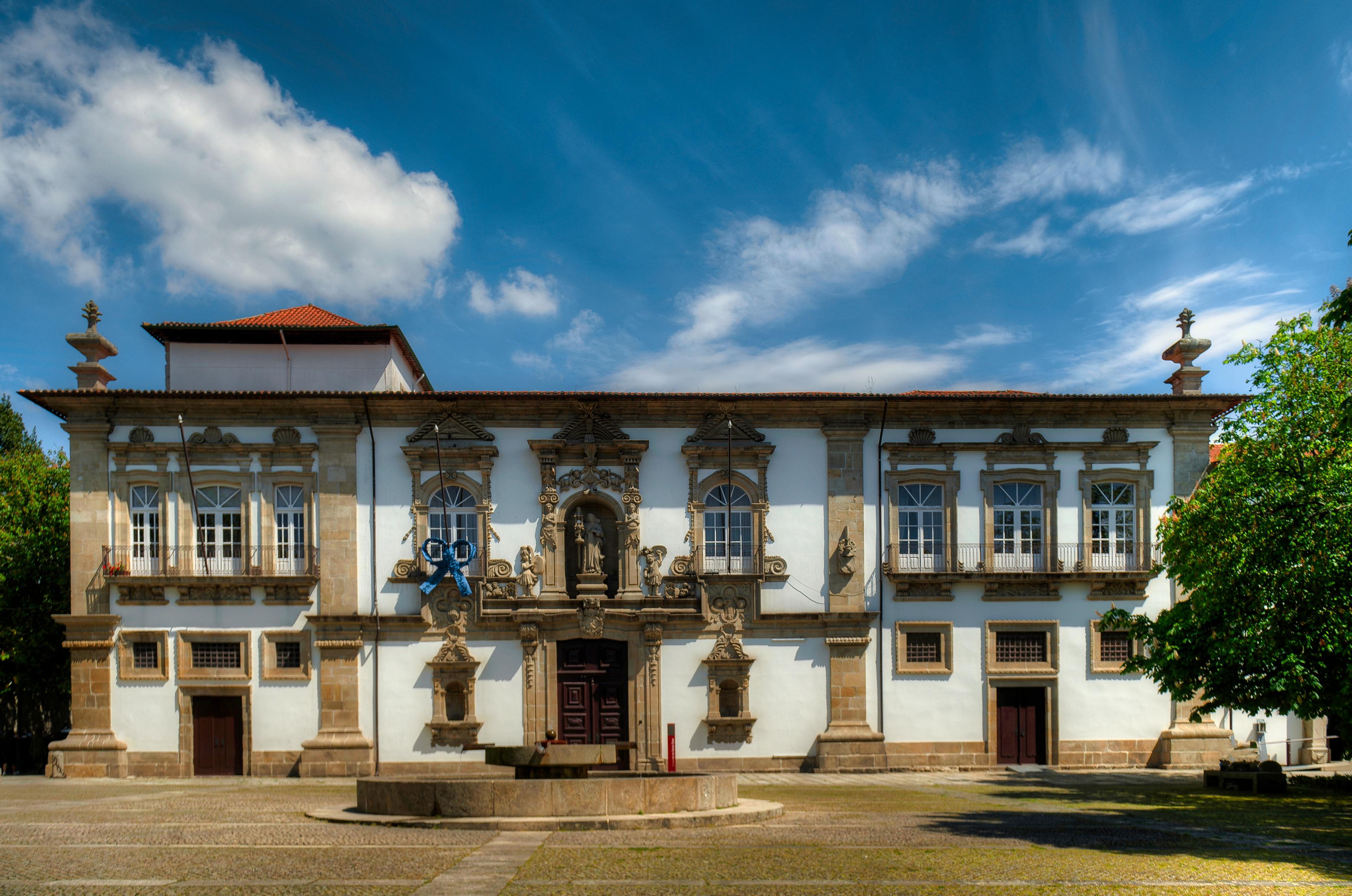 A stone fountain stands before the ornate, symmetrical facade of Convento de Santa Clara.