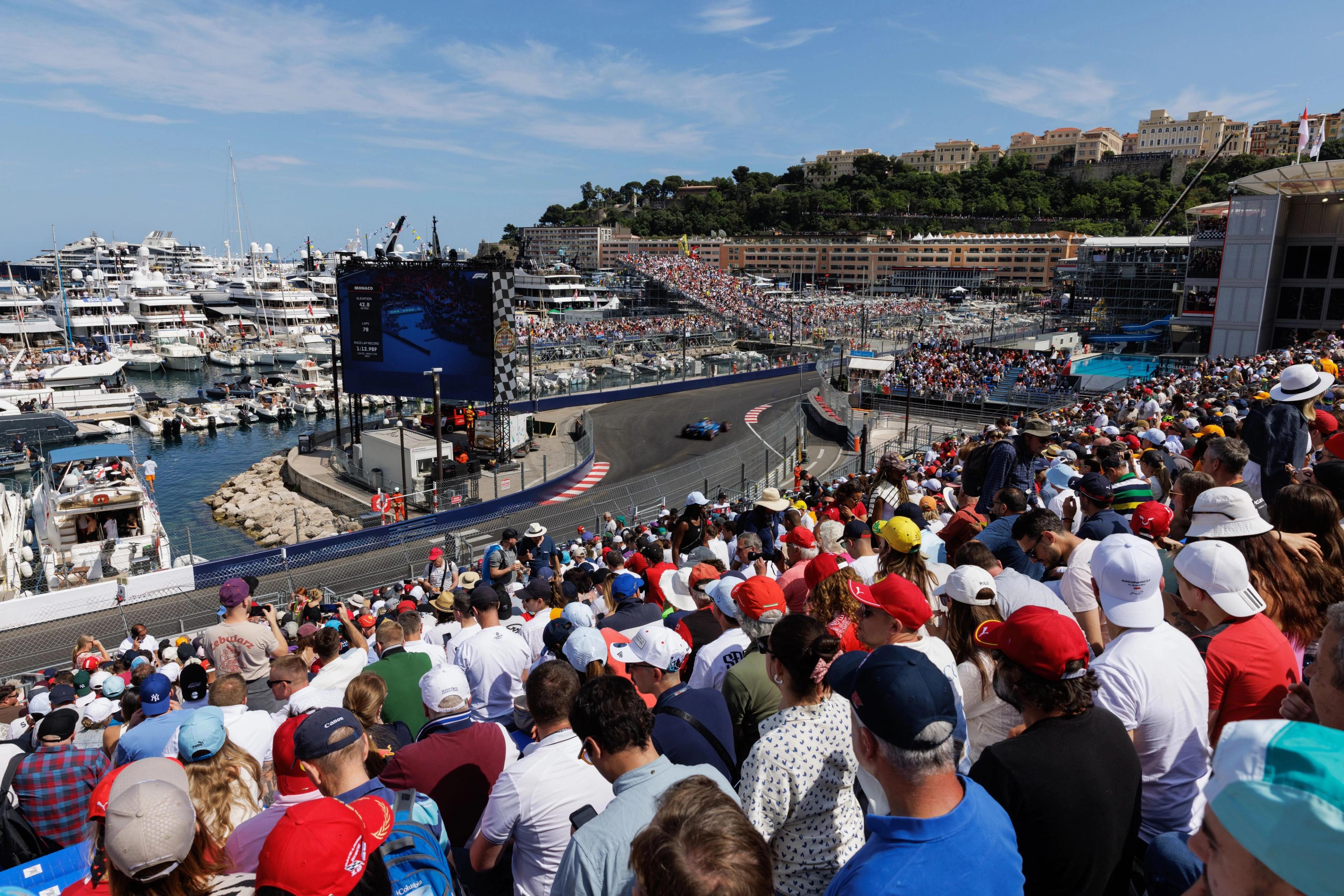 Spectators watching the iconic Formula 1 Monaco Grand Prix from the grand stand, which overlooks Port Hercules and the harbor section between the Tabac corner and the Swimming Pool chicane.