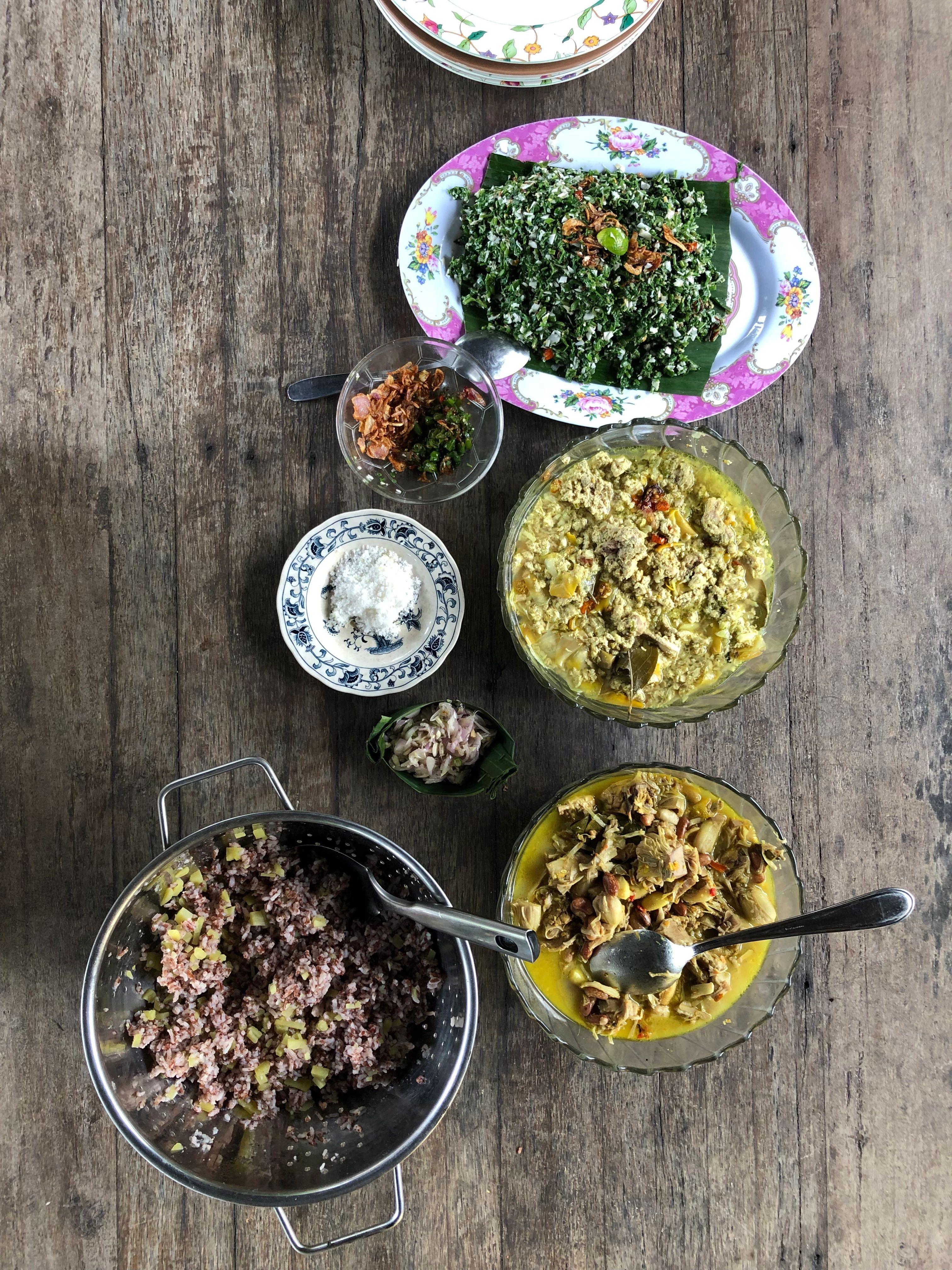 Balinese bumbu paste ingredients including lemongrass, garlic, and chilies resting upon a wooden board.