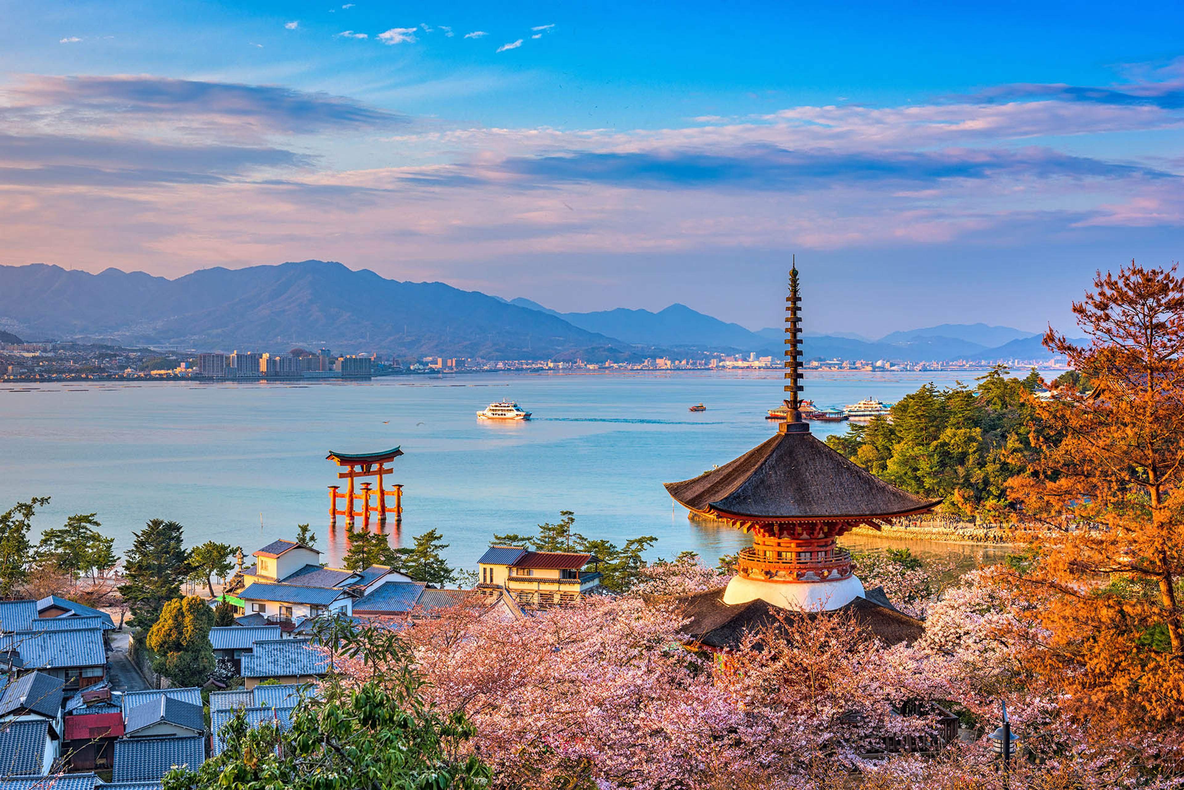 Miyajima Island’s iconic Shinto landmarks framed by cherry blossoms in spring in Hiroshima, Japan./Shutterstock