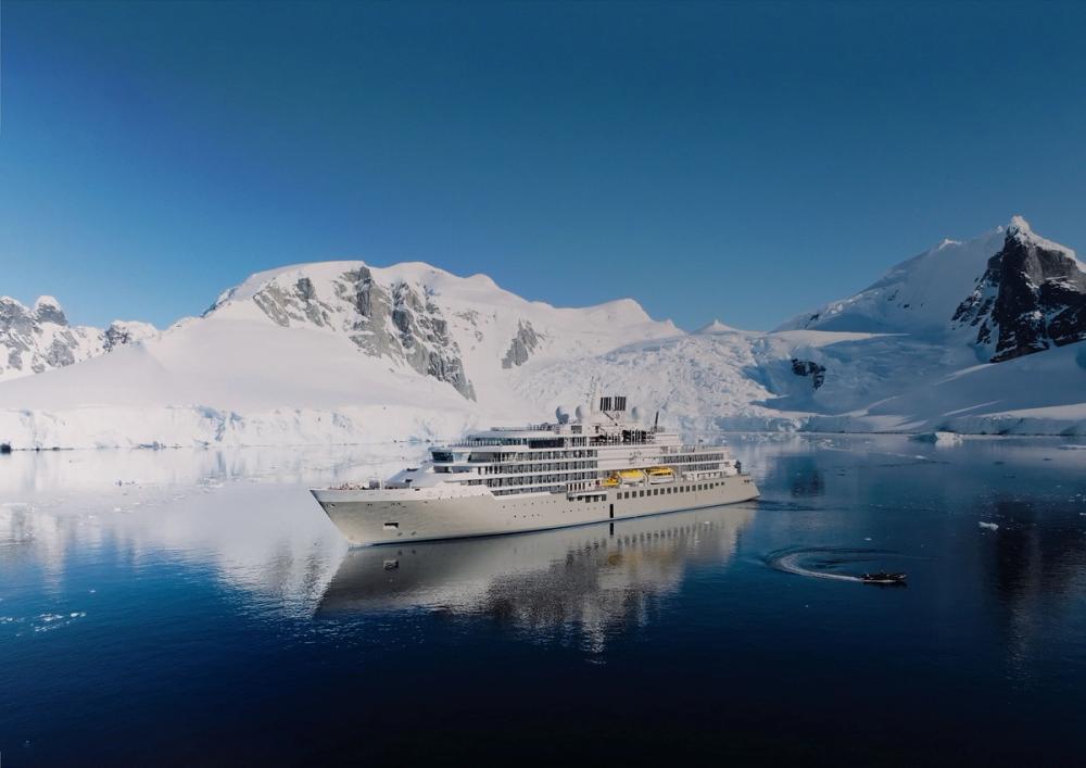 Silver Endeavour at anchor in still water beneath snow-covered peaks in Antarctica