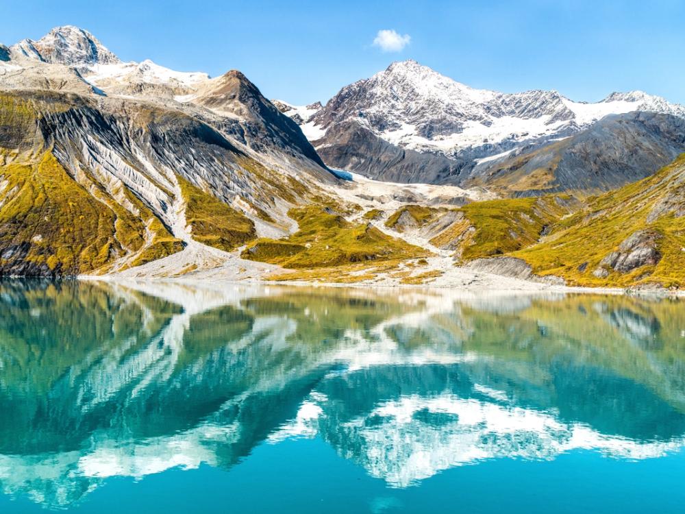 Snow-capped mountains reflected in glacial water in Alaska