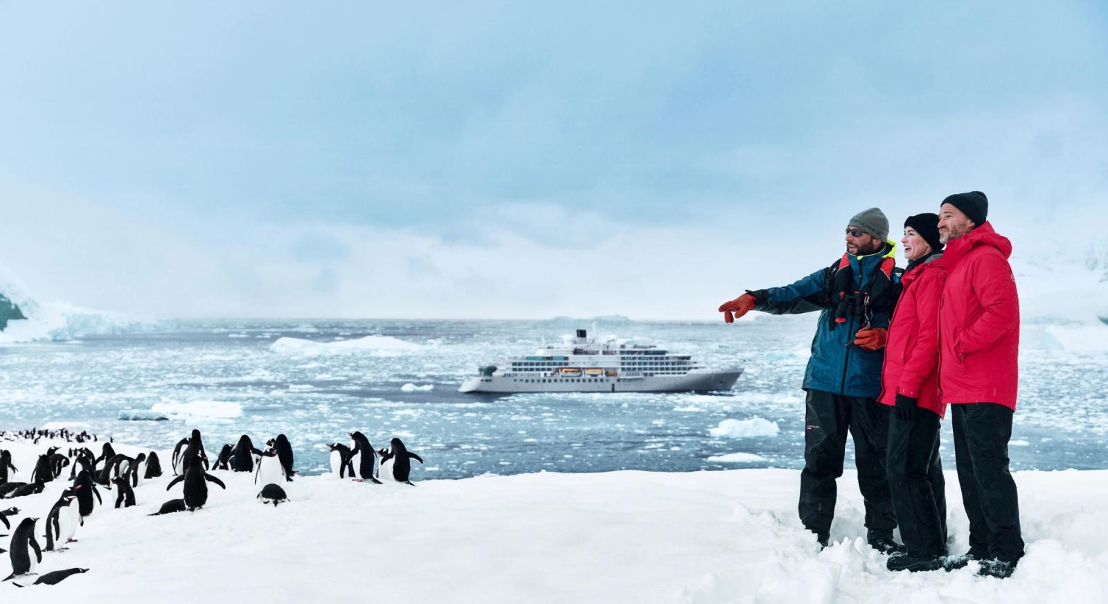 Silversea expedition guide pointing out a penguin rookery with a Silversea ship in Antarctic waters