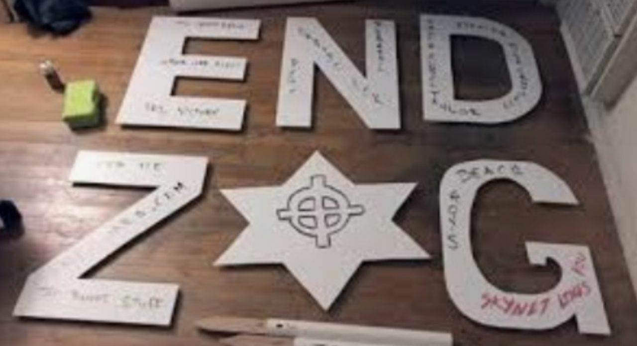 On a wooden floor are white cutouts to the letters "END ZOG". The "O" in ZOG is replaced with a Star of David. A Nazi-styled Celtic Cross is drawn on it. Many words are writte non the letters.