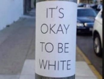 Une affiche sur un lampadaire qui dit 'C'est normal d'être blanc'.