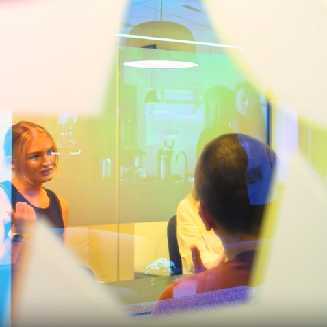 Looking through a meeting room window, where employees have meeting