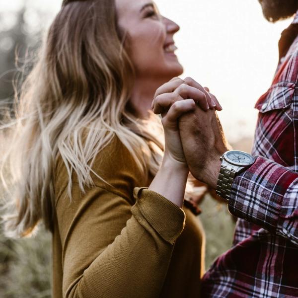 Ett par står mot varandra och håller varandras händer