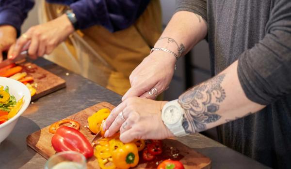 To damer står ved kjøkkenbenken og hakker grønnsaker. bilde.