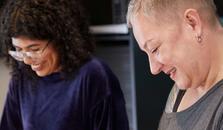 To damer står ved kjøkkenbenken og hakker grønnsaker. bilde.