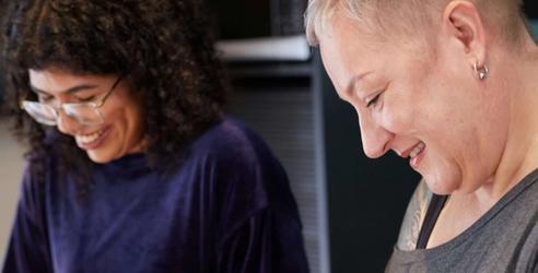 To damer står ved kjøkkenbenken og hakker grønnsaker. bilde.