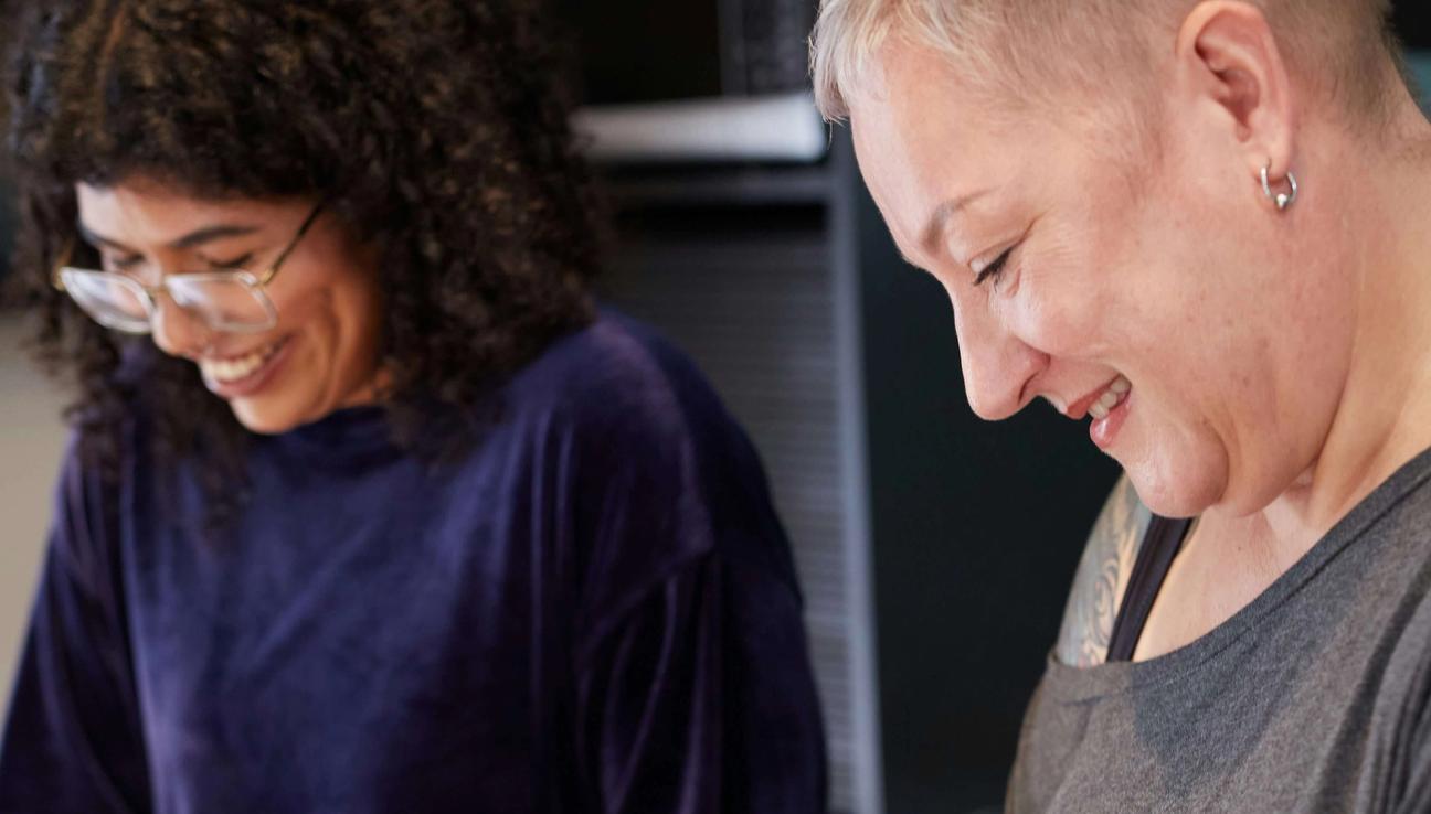 To damer står ved kjøkkenbenken og hakker grønnsaker. bilde.