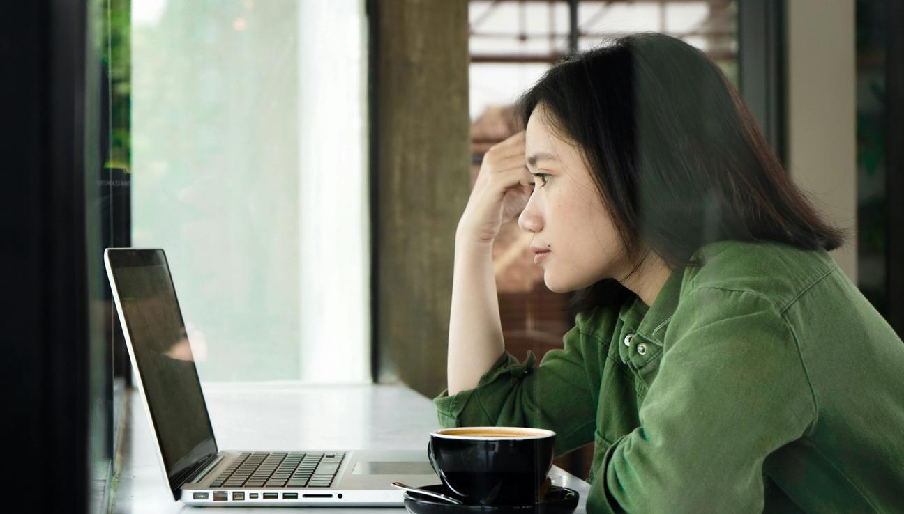 Jente i grønn skjorte ser på skjerm. foto.