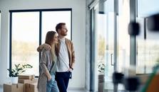 Ungt par har nettopp flyttet inn. De står sammen og ser ut gjennom glassveggen. bilde.