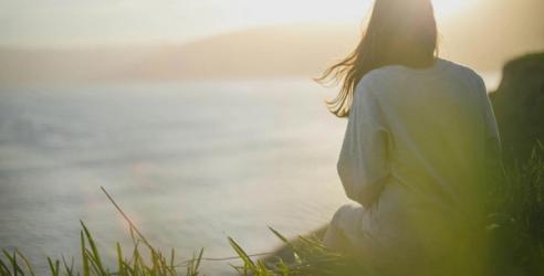 En kvinna sitter högt upp och ser ut över havet