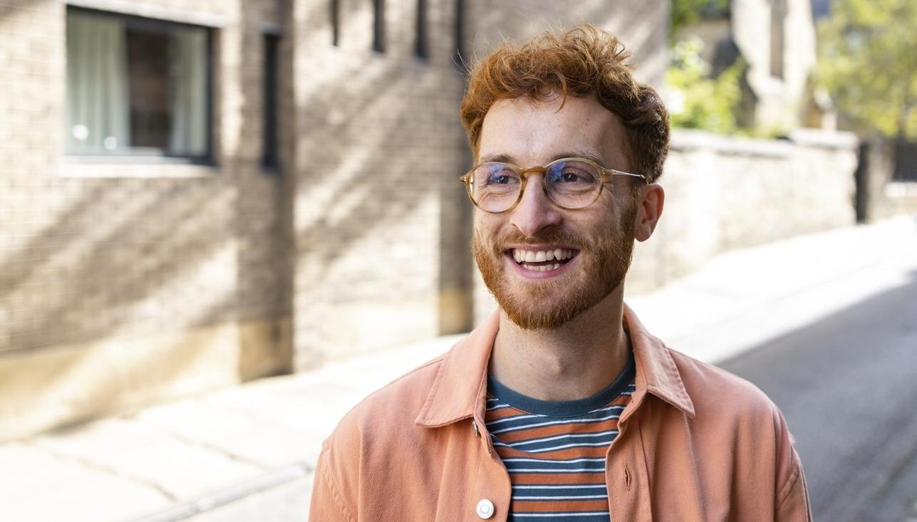 Rödhårig man ute på gatan. Solen skiner. foto.