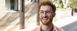 Rödhårig man ute på gatan. Solen skiner. foto.