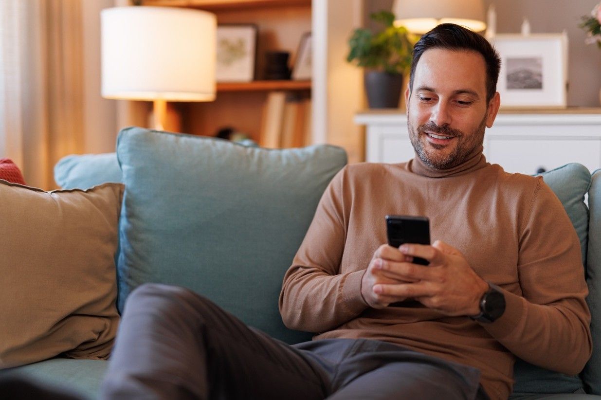 Man sitting on the sofa, surfing on his mobile phone. picture.