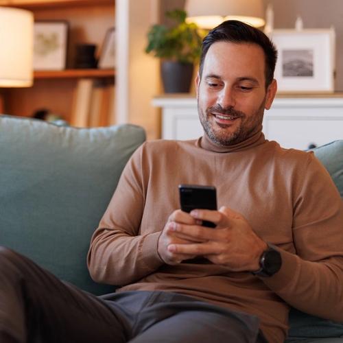 Man sitting on the sofa, surfing on his mobile phone. picture.