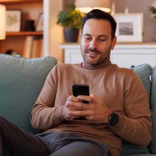 Man sitting on the sofa, surfing on his mobile phone. picture.