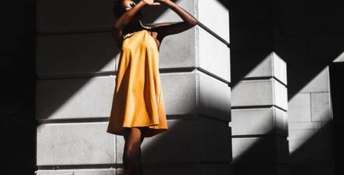 Kvinne i gul kjole holder opp hendene for sollyset. bilde.