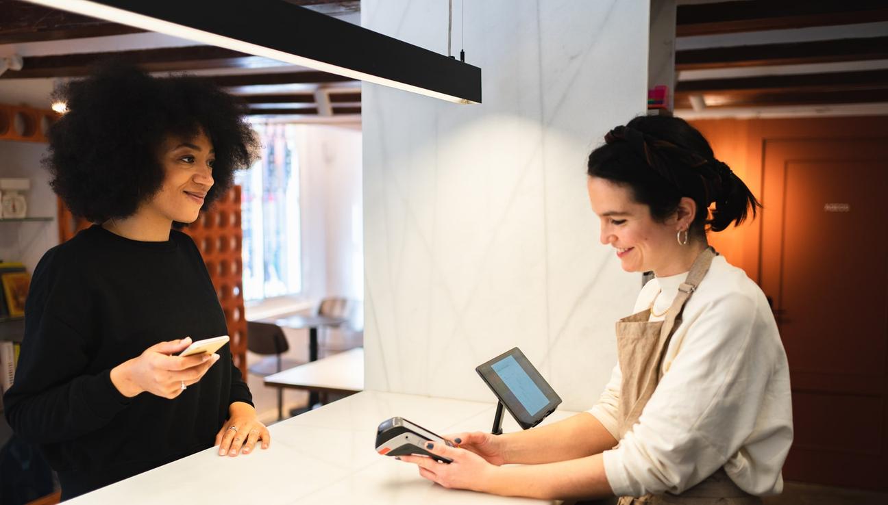 En kvinna väntar på att få betala med mobilen i receptionen