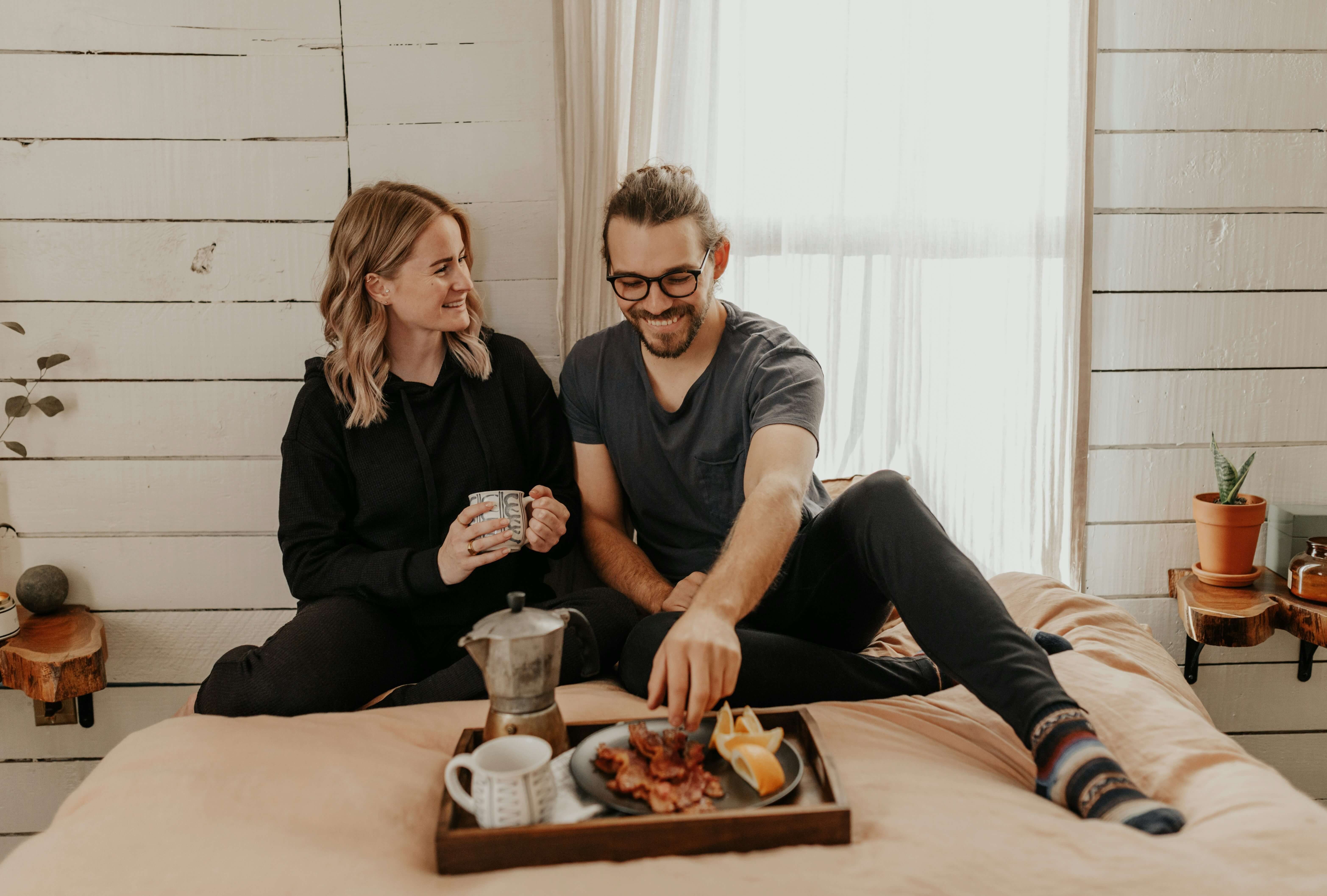 Par spiser frokost i sengen. De smiler. bilde.