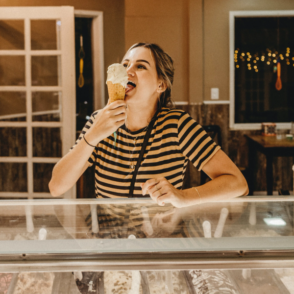 En kvinna äter mjukglass vid en kyldisk med glass