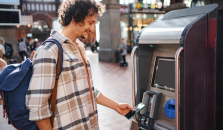 En mann kjøper togbillett og betaler med Morrow Bank kredittkort i mobilen. bilde,