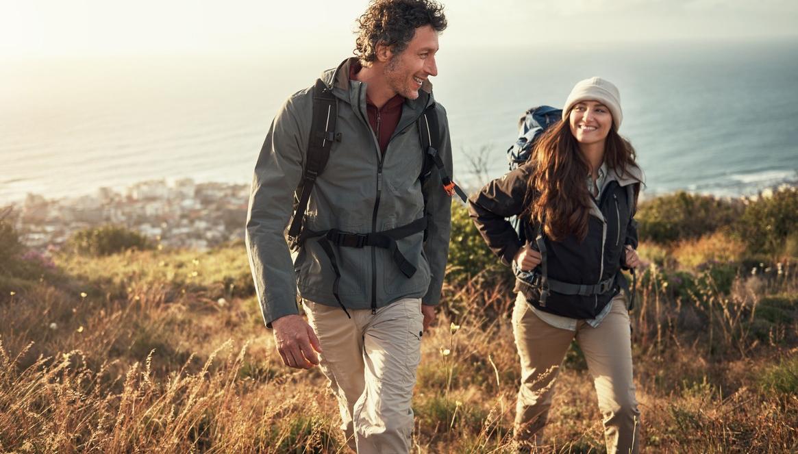 Mies ja nainen kävelevät. Heillä on reput selässään. kuva.