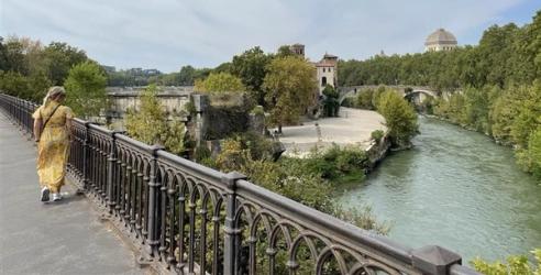 Dame i gul kjole på bro i Italia, med reiseforsikring fra Morrow Bank kredittkort. bilde.