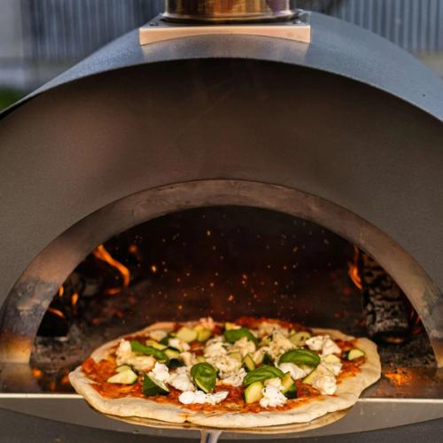 En pizza på väg in i vedeldad pizzaugn