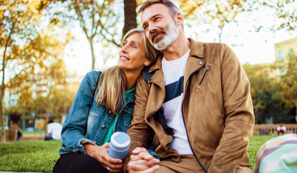 Man och kvinna som sitter ute och håller handen. De är nöjda och glada. bild.