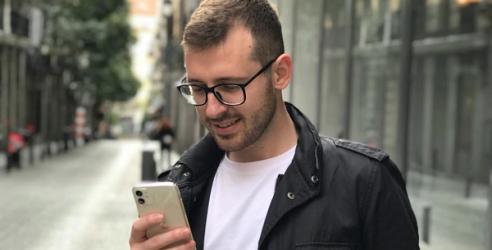 En man i svart jacka står med sin mobil