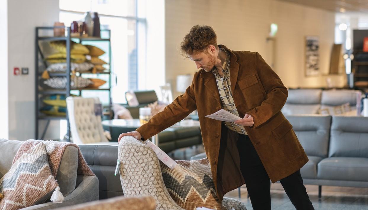Man skal kjøpe sofa. Han vurderer utsatt betaling. bilde.