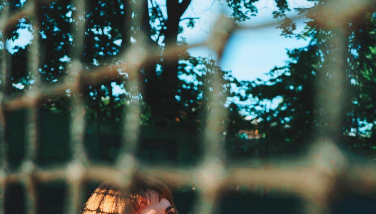 Dame sitter i hvite klær på tennisbanen. Det ser ut som tennisballer rundt henne, men når du ser nærmere er det sitroner. bilde.