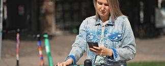 Kvinne betaler elsparkesykkel med Morrow Bank kredittkort i mobilen. bilde.
