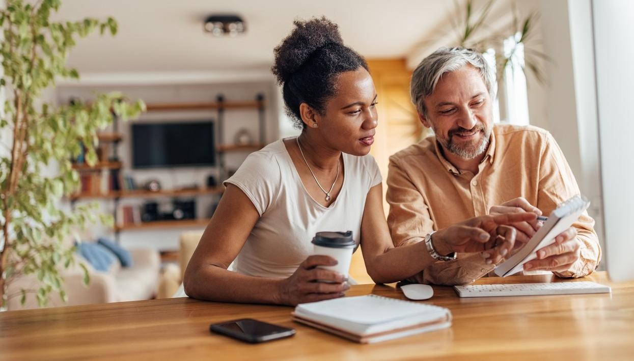 Mann og kvinne sitter ved kjøkkenbordet og lager budsjett. bilde.