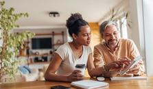 Mann og kvinne sitter ved kjøkkenbordet og lager budsjett. bilde.