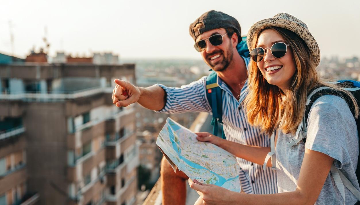 Ett par på resa. De ser på en karta och pekar ut över stan. foto.