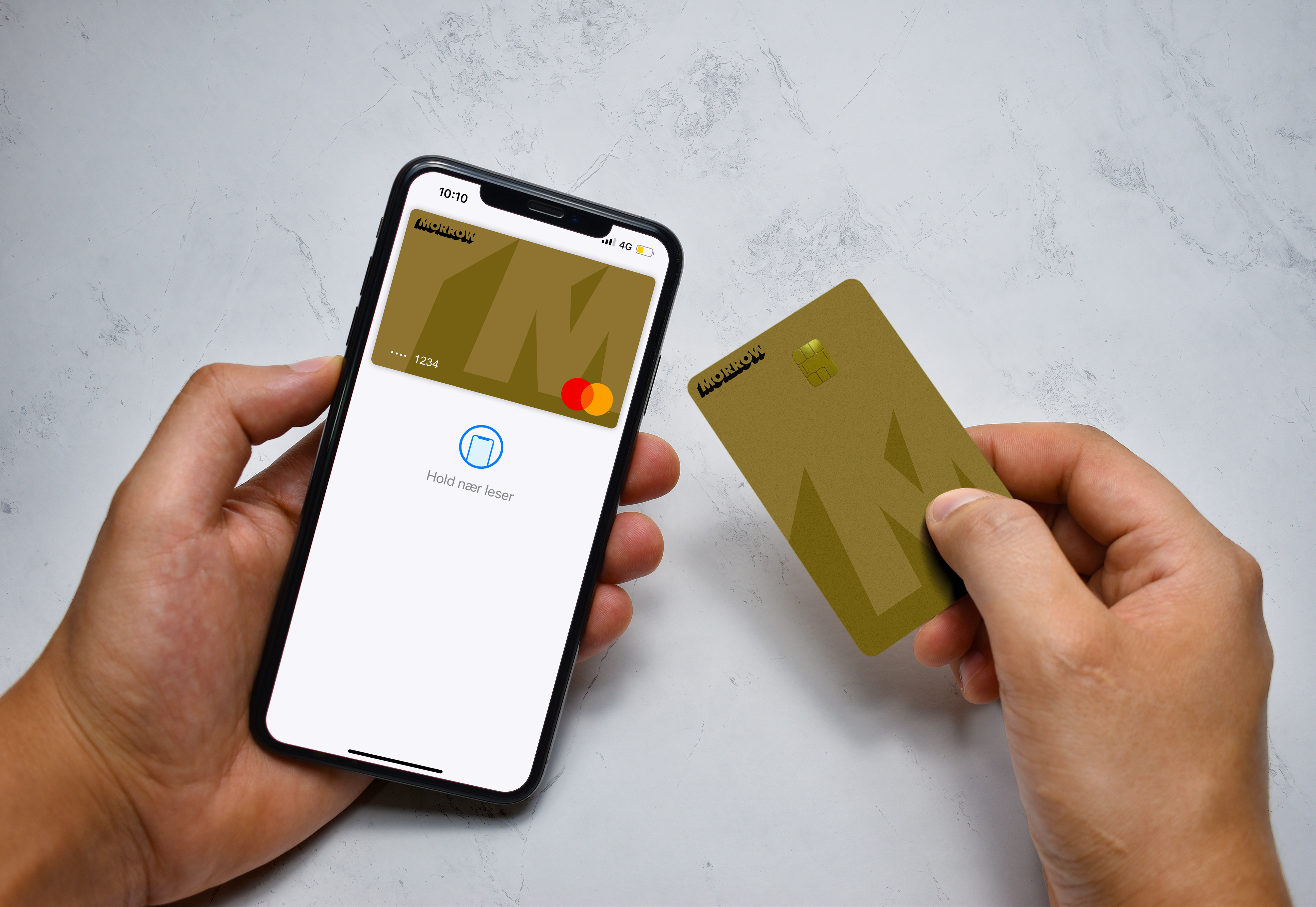 Kädet pitelevät Morrow Bankin luottokorttia sekä matkapuhelinta, jossa näkyy digitaalinen luottokortti. Valokuva.