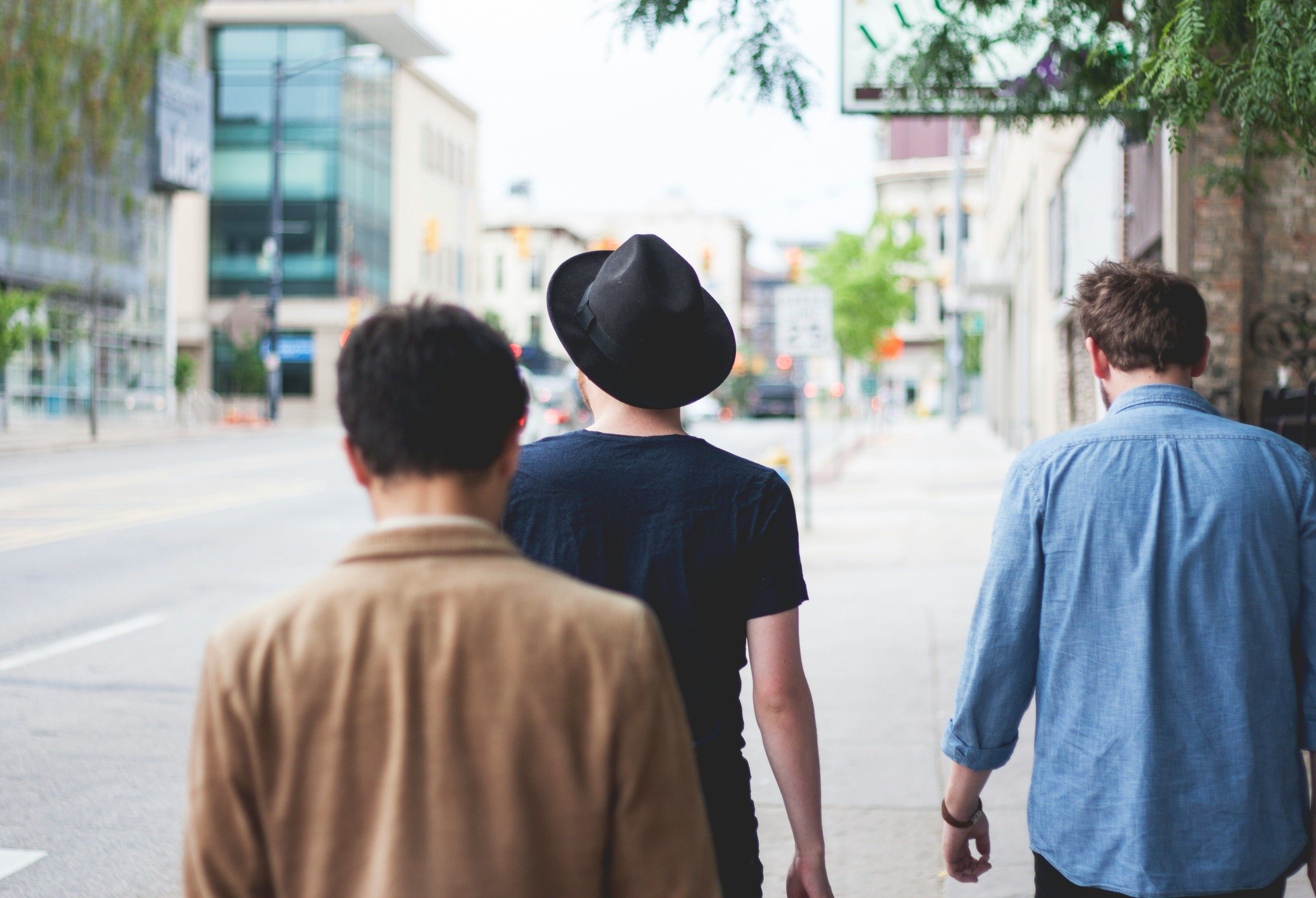 Kolme miestä lomamatkalla kävelemässä tietä pitkin. Valokuva.