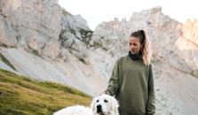 En kvinna och hennes hund vandrar i bergen.