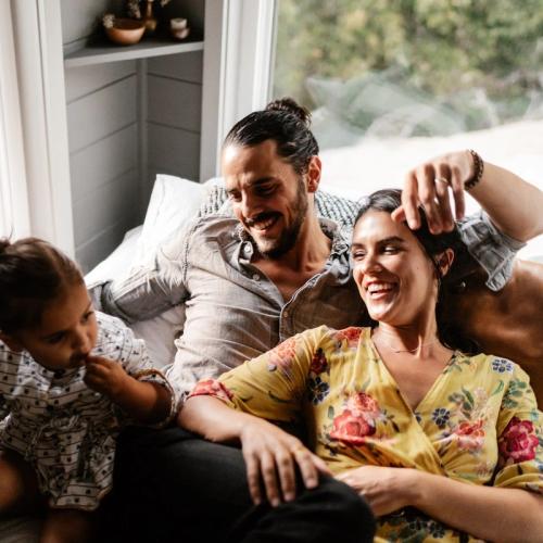 Familie på tre koser seg i sofaen. bilde.
