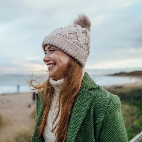 Leende tjej med mössa och varma kläder vid havet. foto.