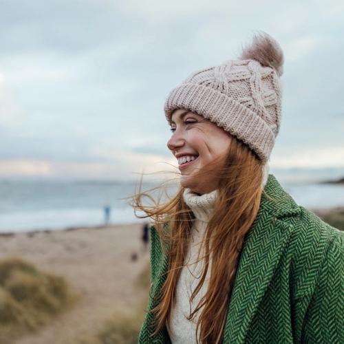 Leende tjej med mössa och varma kläder vid havet. foto.