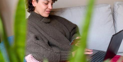 Dame med PC på fanget og et kredittkort i hånden