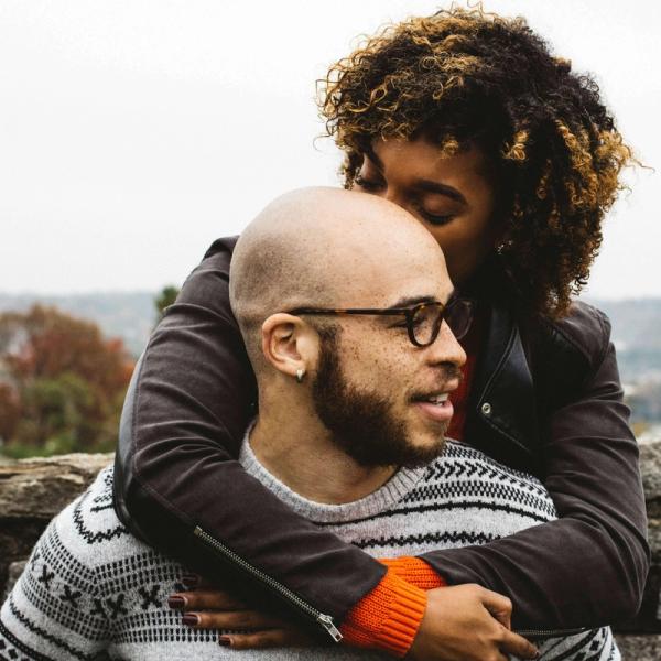 En kvinna står bakom en man och håller om honom